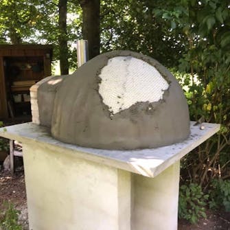 Pizzaovn pudses op med tynd pudsblanding Pizzaovn udendørs pudses op med et lag tynd pudsblanding